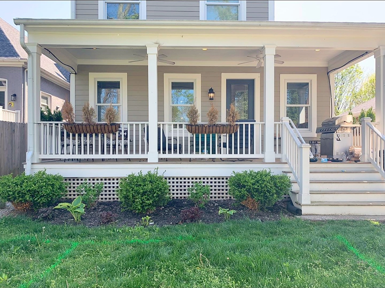 Finished wraparound front porch with white railings and columns